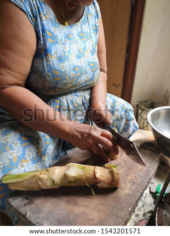 A woman cuts Sri Lankan traditional fruits on a wooden chopping block.