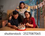 A woman is cutting a birthday cake with candles while two other people look on