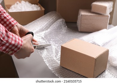 Woman cutting bubble wrap at table in warehouse, closeup - Shutterstock ID 2160103715