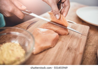 Woman Cutting Chicken Breast On The Table