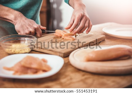 Woman cutting chicken breast on the table