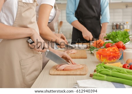 Woman cutting chicken fillet at cooking classes