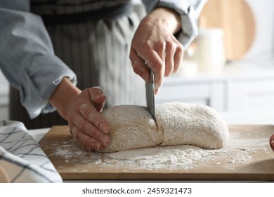 Woman cutting dough at white wooden table in kitchen, closeup - Powered by Shutterstock