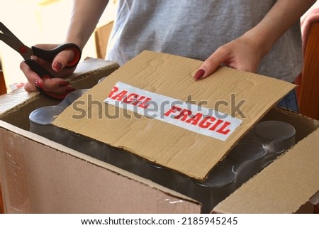 woman cutting a fragile box with scissors