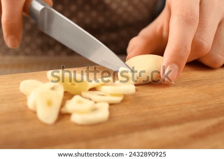 Woman cutting fresh garlic at wooden table, selective focus