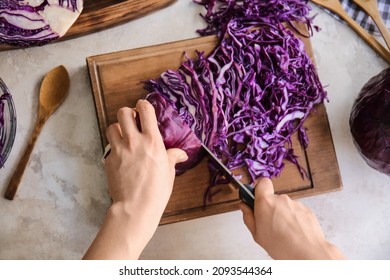 Woman cutting fresh purple cabbage on table - Powered by Shutterstock