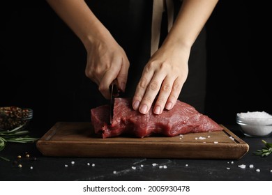 Woman cutting fresh raw meat at black table, closeup - Powered by Shutterstock