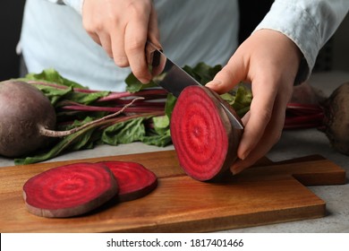 Woman cutting fresh red beet at table, closeup - Powered by Shutterstock