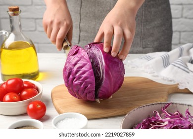 Woman cutting fresh red cabbage at white wooden table, closeup - Powered by Shutterstock