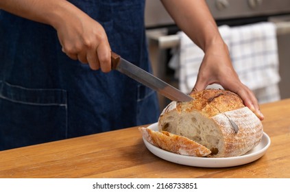 Woman Cutting Freshly Baked Sourdough Bread.