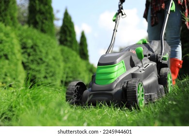Woman cutting grass with lawn mower in garden on sunny day, closeup - Shutterstock ID 2245944601
