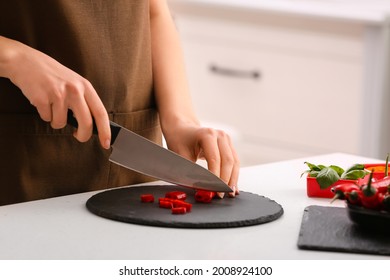 Woman Cutting Hot Chili Pepper In Kitchen