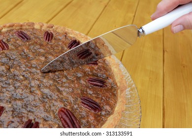 Woman cutting into a home-made pecan pie on a wooden table