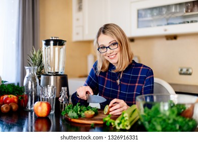 Woman cutting kiwi fruit in kitchen. Female preparing smoothie. Fresh organic food