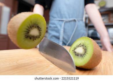 Woman Cutting A Kiwifruit In Half