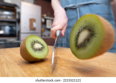 Woman Cutting A Kiwifruit In Half