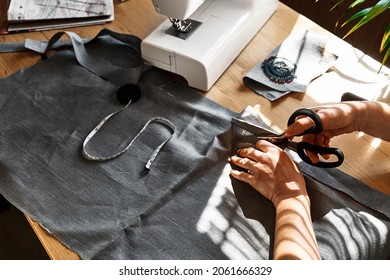 Woman cutting out a pattern paper in linen fabric. Seamstress sewing on the sewing machine in small studio. Fashion atelier, tailoring, handmade clothes concept. Slow Fashion Conscious consumption - Shutterstock ID 2061666329