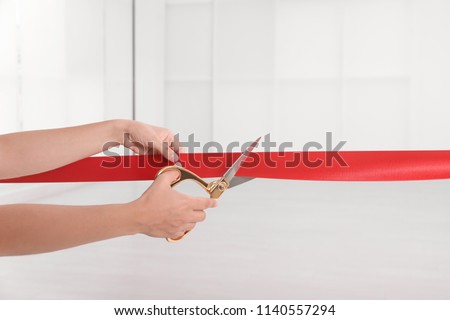 Woman cutting red ribbon on blurred background. Festive ceremony