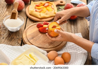 Woman cutting ripe peaches for tasty galette at table - Powered by Shutterstock