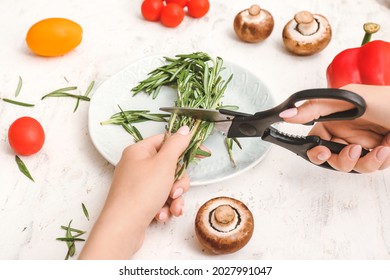 Woman cutting rosemary in kitchen - Powered by Shutterstock