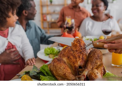 Woman Cutting Tasty Turkey Near Blurred African American Family