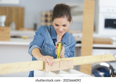 Woman Cutting Wood With A Handsaw In Her Kitchen