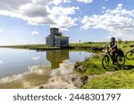 Woman cycles on an e-bike through the Po Delta in Northern Italy ( Valley of Comacchio )
