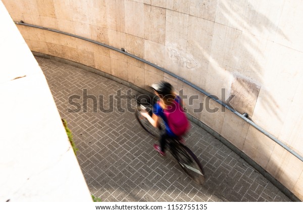 Woman cycling in the city from the underground\
during sunshine