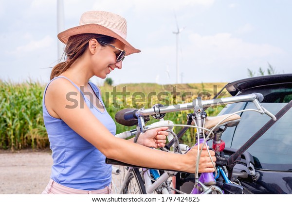 Woman\
cycling in countryside adult woman caucasian pulling bikes from\
bike rack woman cycling in nature in\
countryside\
