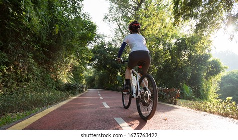 Woman cycling on bike path at sunrise park - Powered by Shutterstock