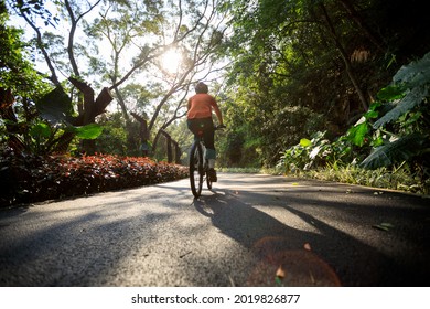 Frau Radfahrerin auf dem Bike-Pfad im Park bei sonniger Zeit