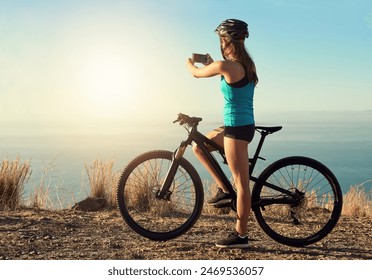 Woman, cyclist and outdoor with photography of view for travel blog, memory and social media post or content creation. Girl, smartphone and mountain for trail riding, cycling and adventure on holiday - Powered by Shutterstock