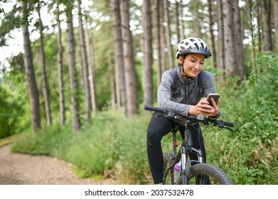 Woman cyclist in the public park using smartphone