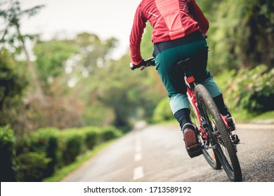 Woman Cyclist Riding A Bike On Sunny Park Trail In Spring