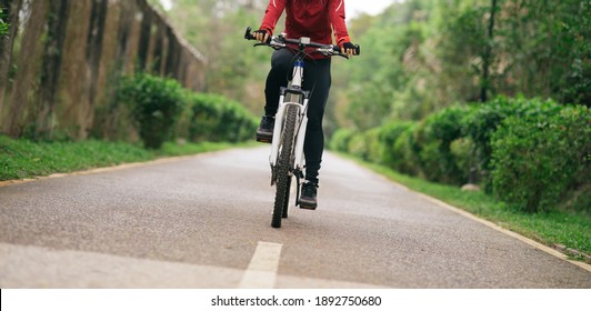 Woman cyclist riding a bike on tropical park trail in spring