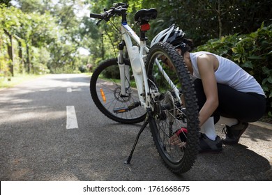 Woman cyclist set the chains of bike  at park on sunny day - Powered by Shutterstock