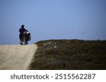 Woman cyclist traveling by bicycle through dirt and dust fields