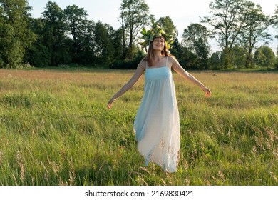 Woman dance ecstatic dance in field. Woman in flower wreath. Summer solstice day.
