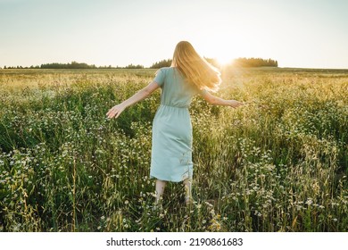 Woman dance in the field on sunset. Defocused, grass on foreground.