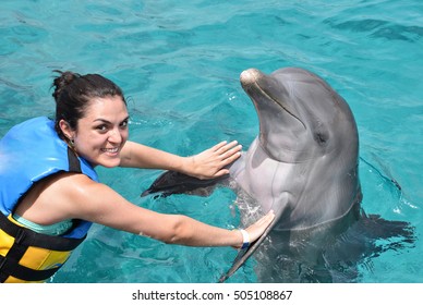 woman dancing with dolphin in blue pool water