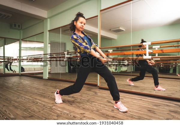 Woman dancing modern dance in a\
choreographic hall with mirrors,  Woman dancer exercising\
alone