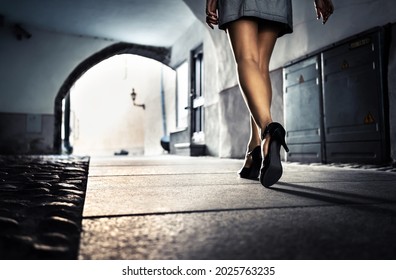 Woman In Dark Alley And City Street At Night Alone. Lonely Scared Girl Walking, Afraid Of Sexual Harassment Or Robber Following. Scary Dramatic Tunnel In Shadow. Fear Danger, Crime Or Robbery Downtown