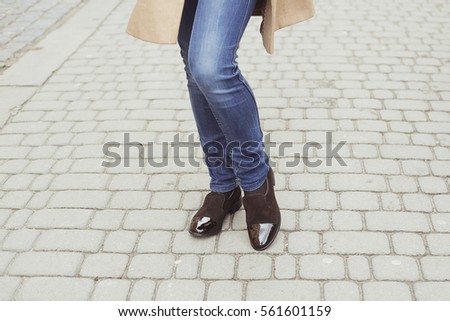 Woman in dark brown suede shoes and jeans on a city street. Fashion & Style