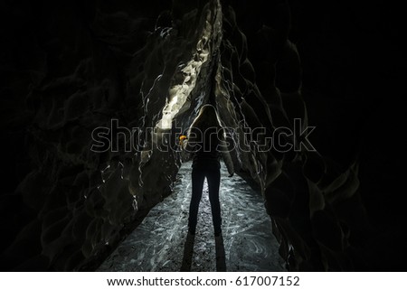 Woman in the dark cave with flaslight. back view. scenist girl between stones wall. 