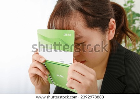 A woman with a dark expression while holding a passbook.

The passbook is written as 
