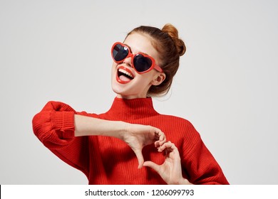 a woman in dark glasses and a red sweater folded her arms in the form of a heart                           