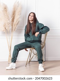 Woman in dark green cotton tracksuit. Warm clothing for winter. Sports style for every day. Vertical. Comfortable