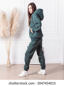 Woman in dark green tracksuit. Warm clothing for autumn or winter. Sports style for every day. In full growth