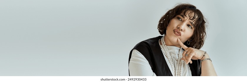 A woman with dark hair wears a pearl necklace and contemplates something off-camera. - Powered by Shutterstock