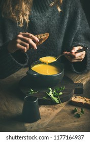 Woman In Dark Winter Sweater Eating Sweet Corn And Shrimp Chowder Soup From Black Bowl With Toasted Bread, Close-up. Autumn Or Winter Warming Food